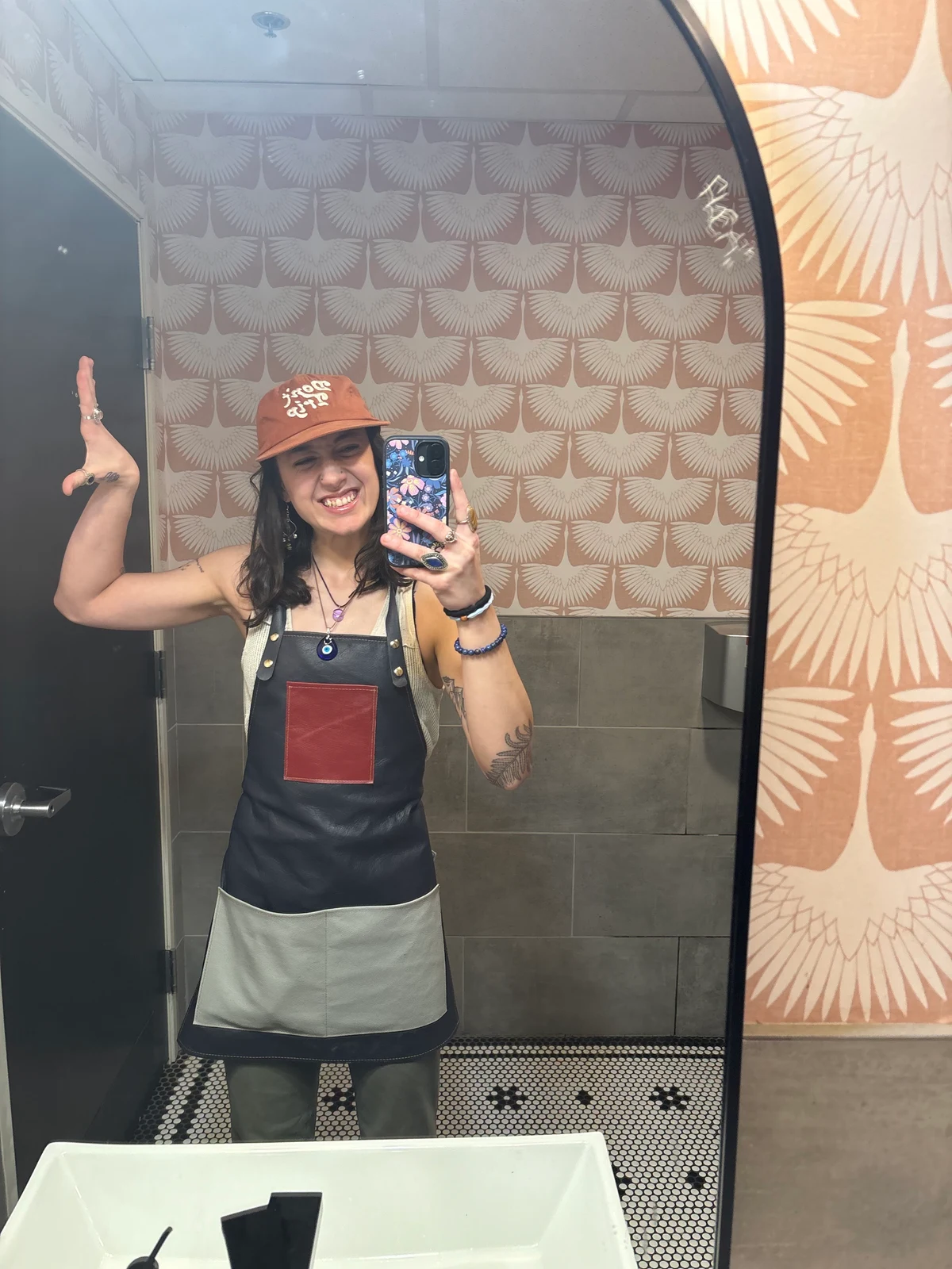 Customer taking a mirror selfie in a dark leather apron with red and light gray pockets