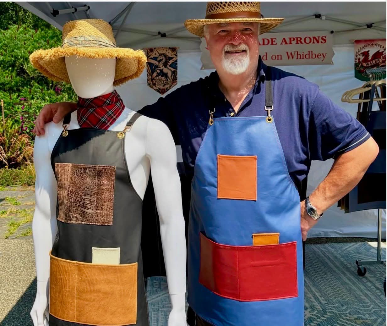 Crispin wearing a blue leather apron beside a mannequin at Coupeville Arts Festival 2026.