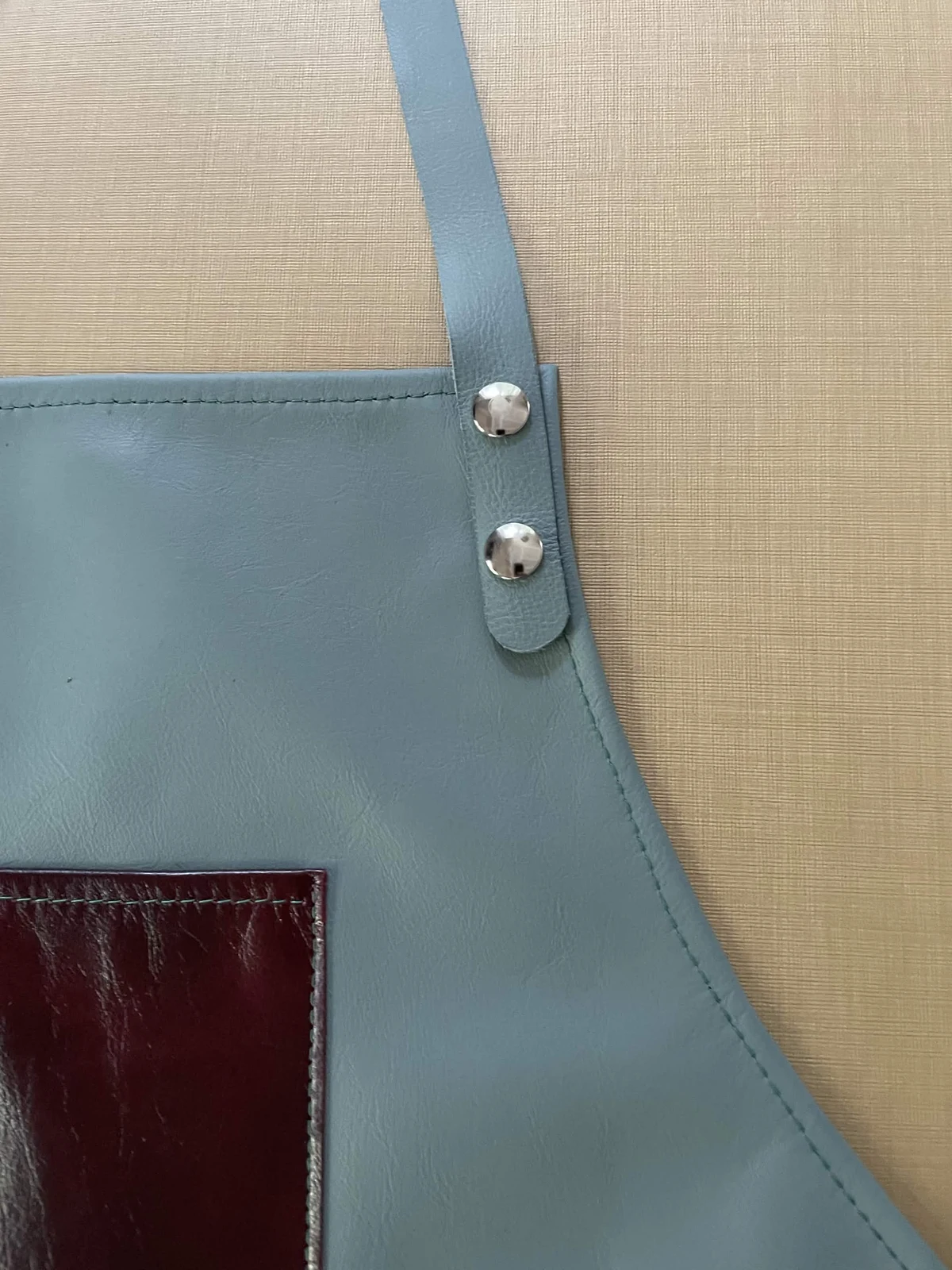 Pale blue leather strap with silver-tone fasteners, tonal stitching, and a burgundy pocket